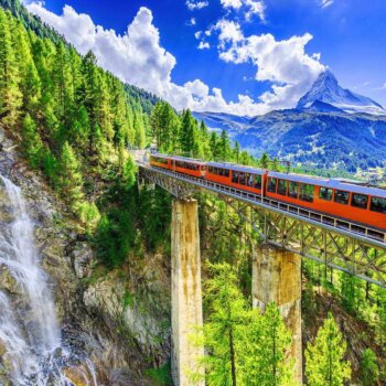 red train on bridge in switzerland mountains