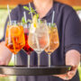 Server holding up a tray of four cocktails