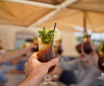 person raising and chinking with a long island ice tea cocktail