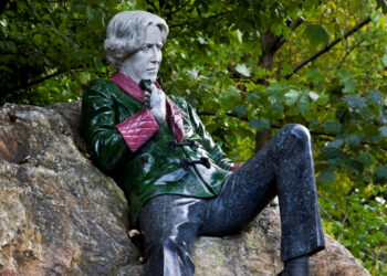 Photo shows the Oscar Wilde statue in Dublin City's Merrion Square. The author is shown reclining atop a stone