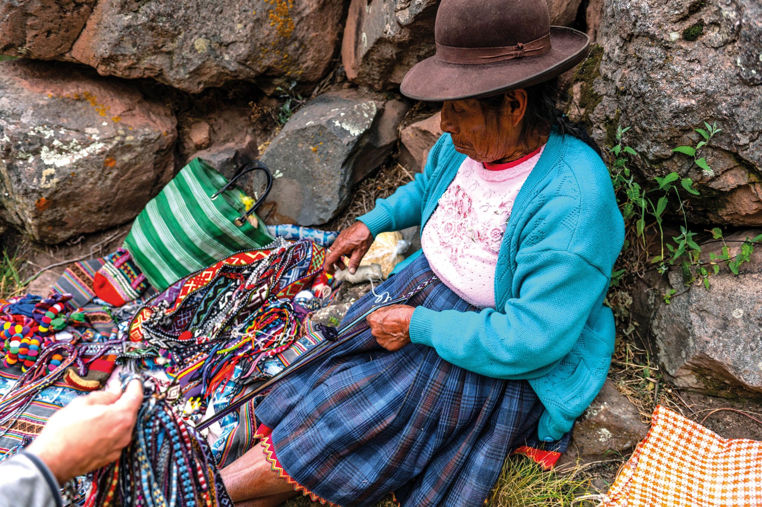 A souvenir seller checks their wares on the route to Pisac