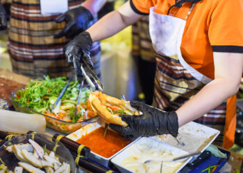 Vietnamese woman serving a traditional vietnamese banh mi sandwich in a street food market