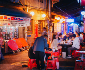 People drinking on plastic chairs outside a casual restaurant in Seoul