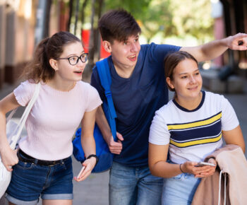 Boy pointing something out to two girls
