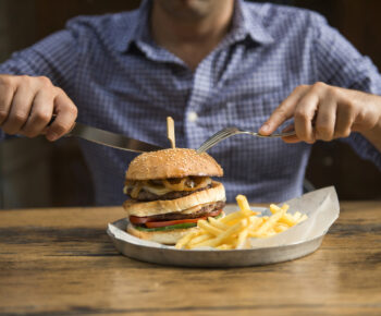Man eating a burger with a knife and fork