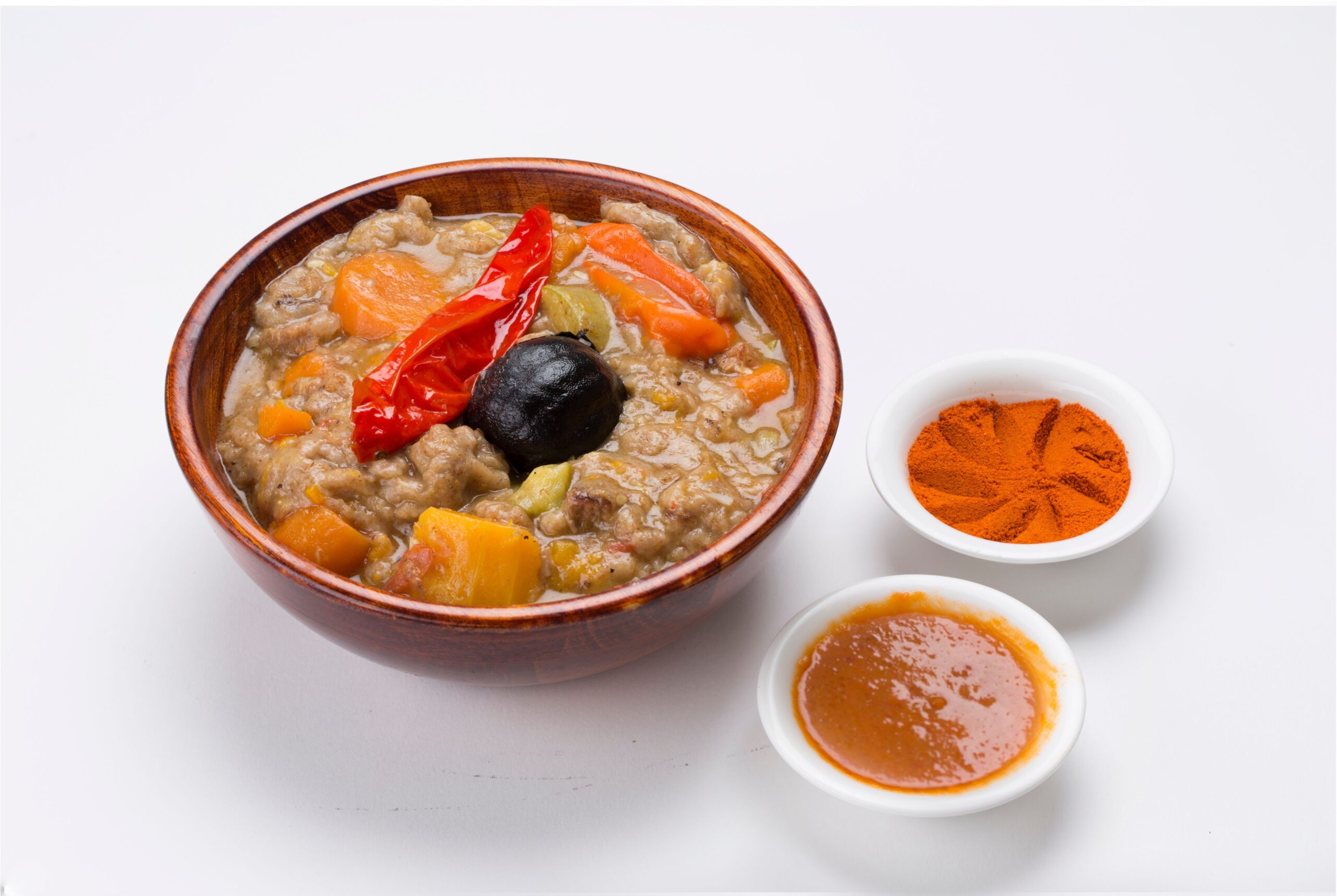 Bread dish with vegetables serviced in a wooden bowl with sauces on the side