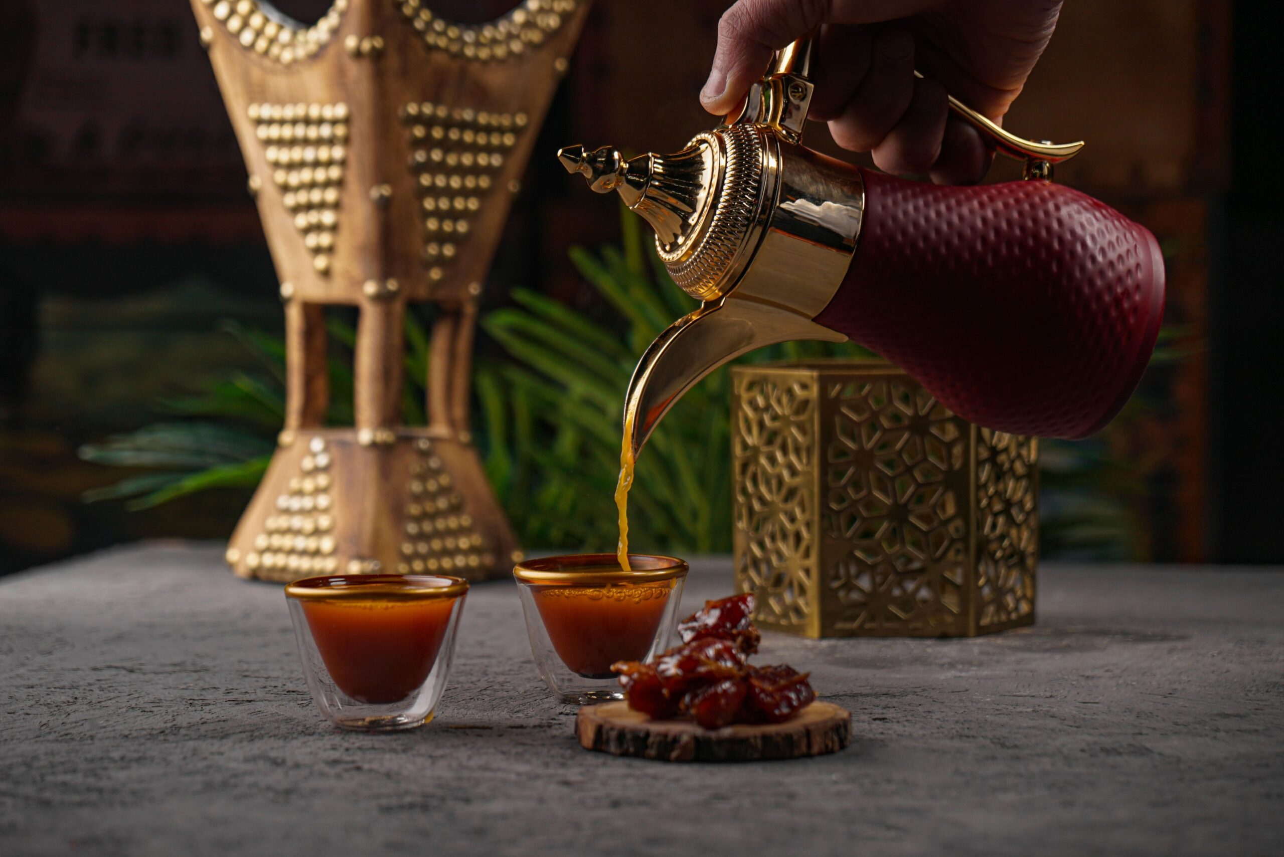 Coffee being poured from the gold teapot into a glass cup
