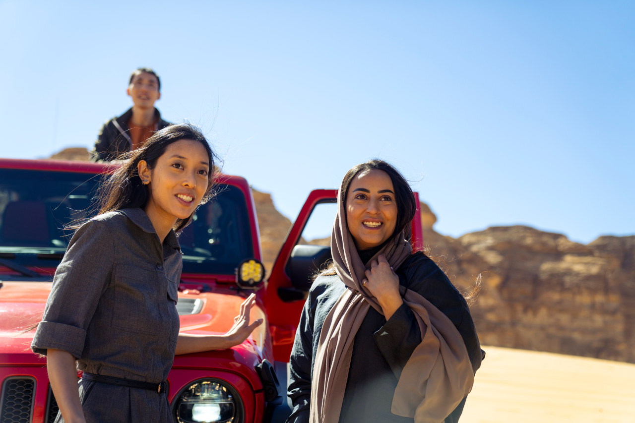 Women stood by a jeep in the desert smiling at something
